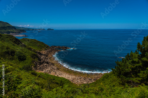 Hidden cove on the Orio coast and in the distance Getaria, Guipuzcoa, Basque country. Excursion from San Sebastián to the town of Orio through Mount Igeldo walking 3 friends.