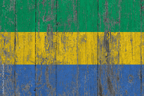 Gabon flag on grunge scratched wooden surface. National vintage background. Old wooden table scratched flag surface.