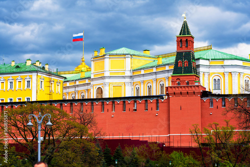 Building of a Grand Kremlin Palace with waving flag of Russian Federation on the roof against Moscow Kremlin towers on a dark, cloudy and stormy sky background