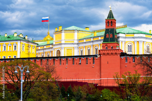Building of a Grand Kremlin Palace with waving flag of Russian Federation on the roof against Moscow Kremlin towers on a dark, cloudy and stormy sky background
