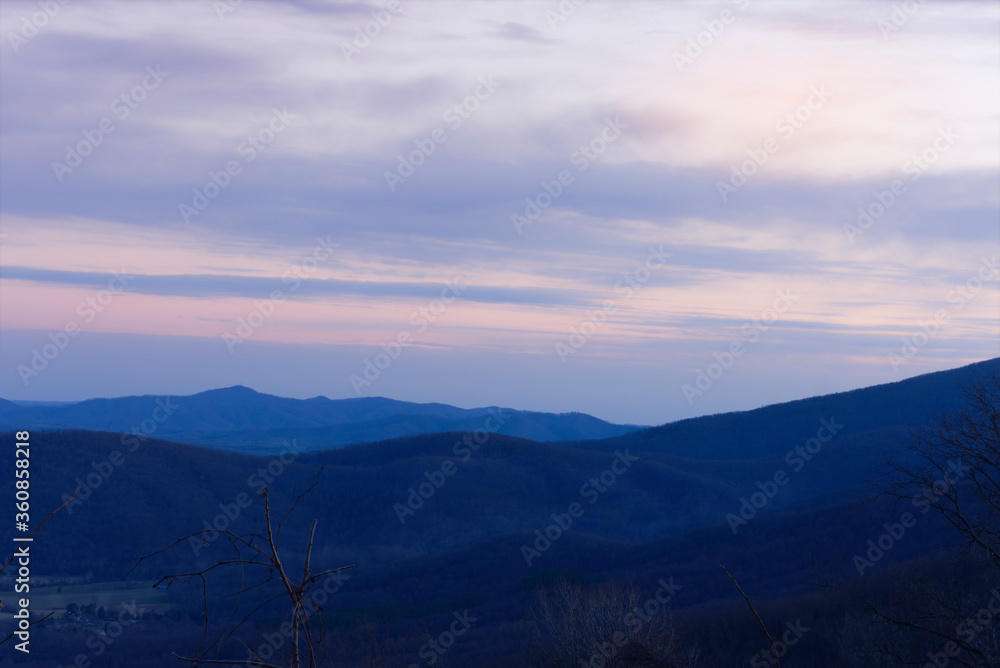The sun sets behind the Blue Ridge Mountains of Virginia resulting in pastel colored skies and fog in the valleys.