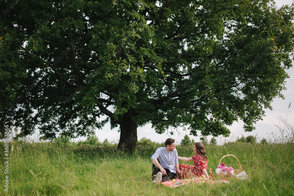 Happy couple sits has mini picnic near the big tree. Non alcoholic picnic Happy couple sits has mini picnic near the big tree. Non alcoholic picnic