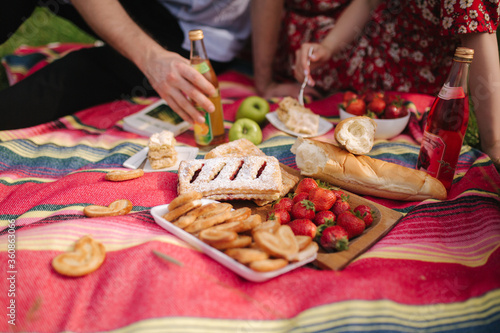 Close up of man and woman has non alcoholic picnic outdoors. Strawberry, lemonade, bread and other snacks