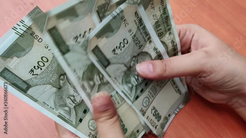 Hands counting new Rs 500 Rupees Indian Currency notes against a wooden bokeh background. photo