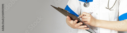 Hand of female doctor with pen writing on prescription blank