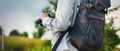 Traveller with backpack and binoculars on green nature background