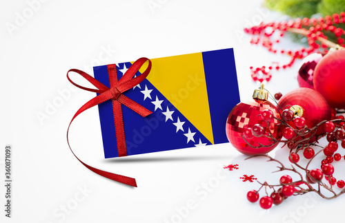 Billede på lærred Bosnia Herzegovina flag on new year invitation card with red christmas ornaments concept