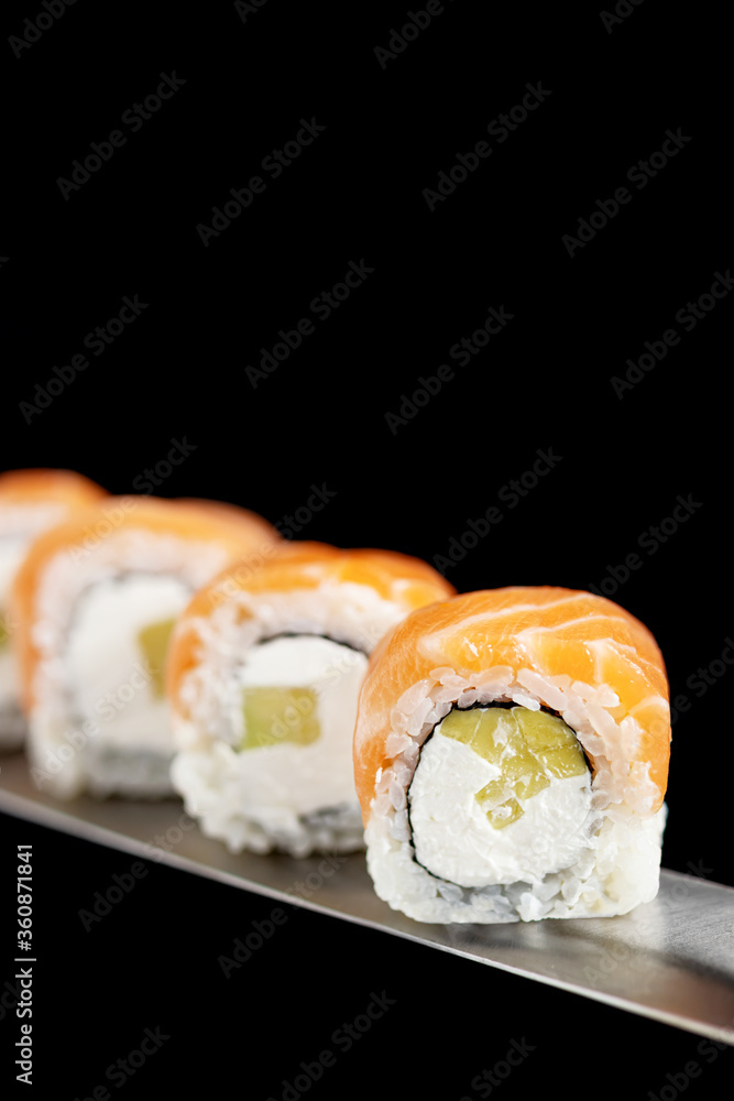 Japanese rolls and seafood sushi on a katana sword on a black background Japanese rolls and seafood sushi on a katana sword on a black background