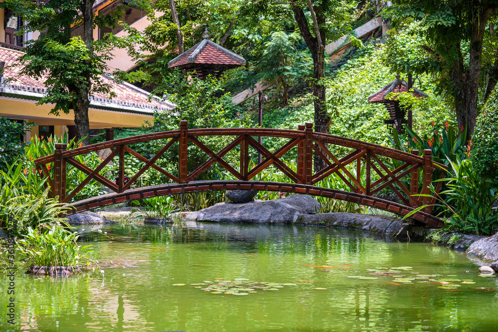 Arched bridge through a decorative pond on a Japanese tropical garden in Danang, Vietnam Arched bridge through a decorative pond on a Japanese tropical garden in Danang, Vietnam