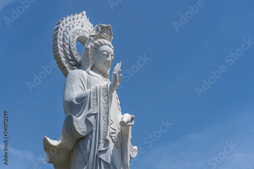 Detail of Lady Buddha statue in a Buddhist temple and blue sky background in Danang, Vietnam. Closeup, copy space