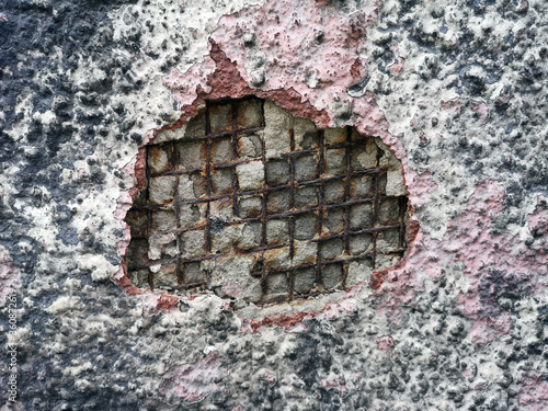 Background, texture. Iron rusted fittings in a breakaway concrete wall and plaster. The iron lattice