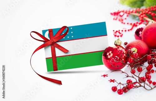 Uzbekistan flag on new year invitation card with red christmas ornaments concept. National happy new year composition.