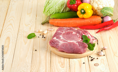 Pork neck Slice on wooden plate on wooden table with vegetables on background