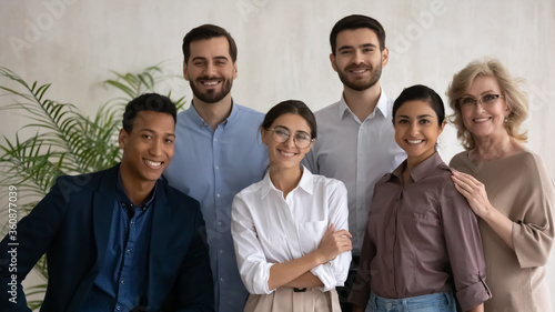 Diverse happy business people successful employees team posing in office, looking at camera, smiling workers group, motivated staff, confident businesswomen and businessmen corporate portrait