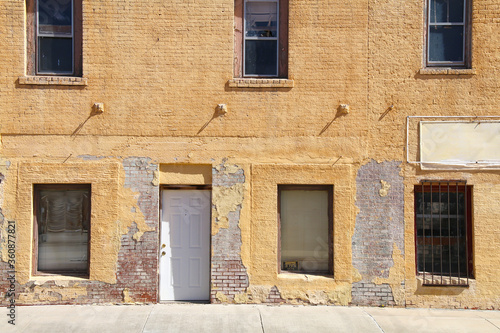 an abandoned empty business shop building front with vintage yellow brick wall © DrewTraveler