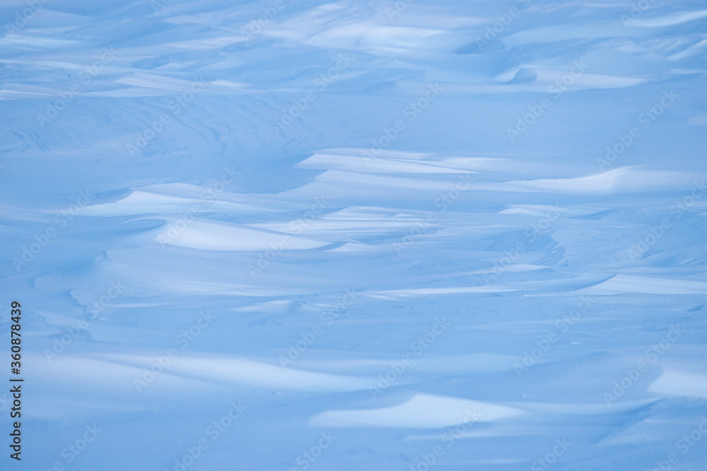 Beautiful winter background with snowy ground. Natural snow texture. Wind sculpted patterns on snow surface. Arctic, Polar region. Beautiful winter background with snowy ground. Natural snow texture. Wind sculpted patterns on snow surface. Arctic, Polar region.