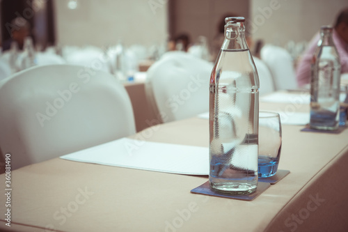 Water bottles on table in meeting room or conference hall with group audience listens speech lecturer in seminar at hotel, business and education meeting concept