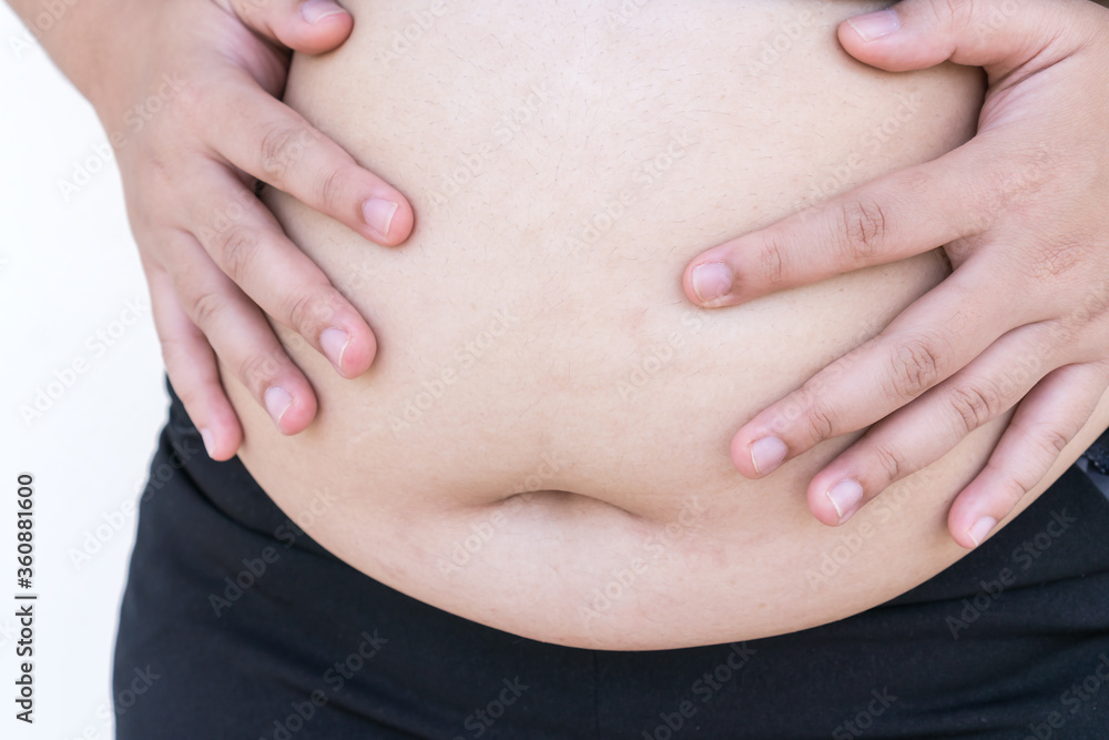 Overweight Fat Asian young woman pinching her belly big in sportswear, overeating problem, obesity. Weight people having more body fat than is optimally, body mass index (BMI), unhealthy concept Overweight Fat Asian young woman pinching her belly big in sportswear, overeating problem, obesity. Weight people having more body fat than is optimally, body mass index (BMI), unhealthy concept
