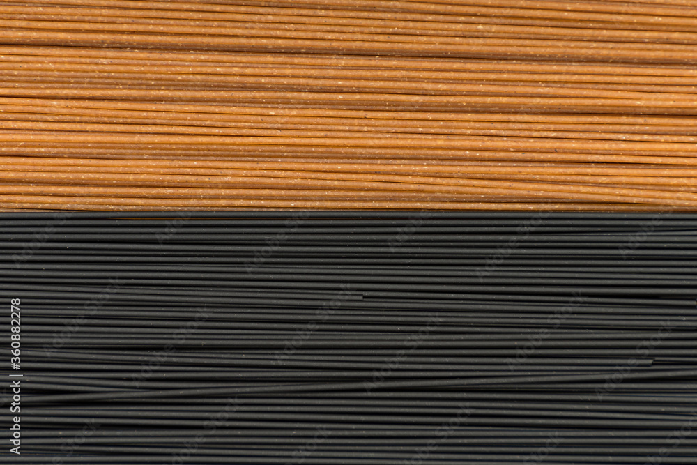 Obraz premium Spaghetti background. Black and brown spaghetti close up. Whole grains