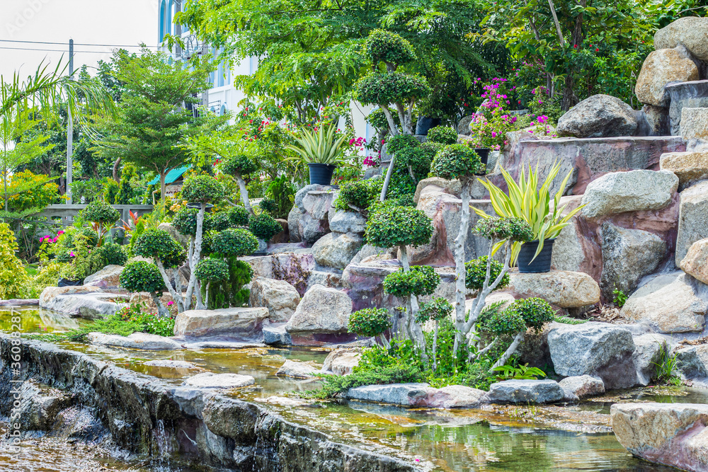 Stone garden with waterfalls and flowers pot decoration in cozy home flower garden on summer. Stone garden with waterfalls and flowers pot decoration in cozy home flower garden on summer.