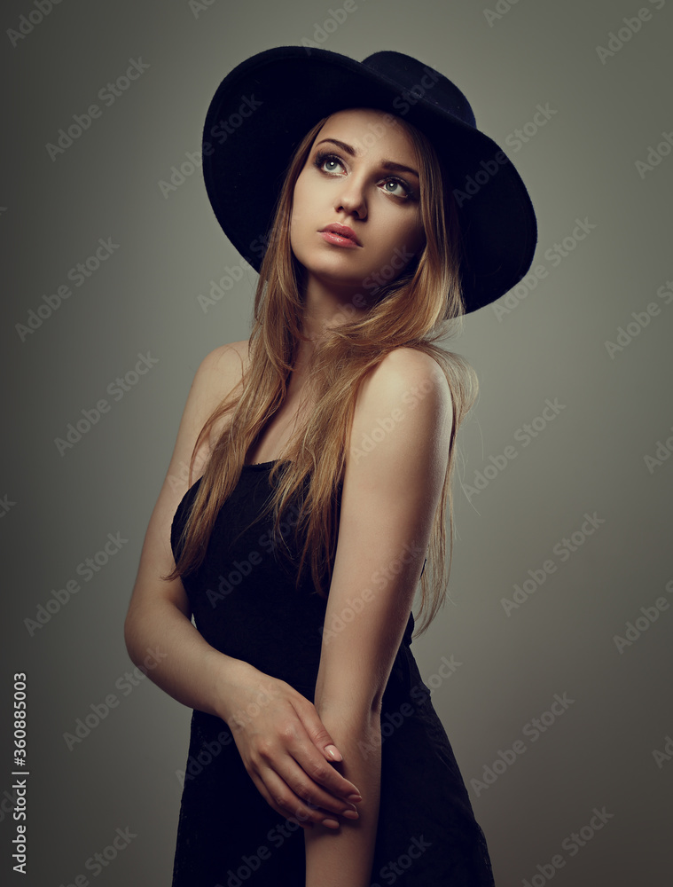 Beautiful makeup woman with long blond hair style in black hat on studio background.. Closeup glamor portrait. vintage toned color Beautiful makeup woman with long blond hair style in black hat on studio background.. Closeup glamor portrait. vintage toned color