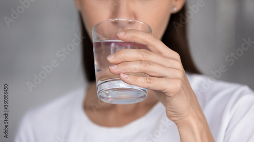 Close up of young woman hold glass drink clear mineral still water manage body balance, millennial female feel thirsty enjoy crystal aqua follow healthy lifestyle, hydration, weight loss concept
