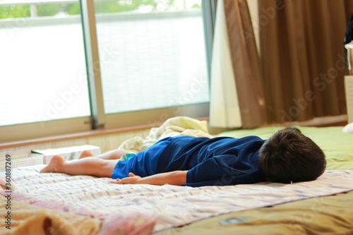 夏バテのため布団でダラダラしている小学生の床の子
