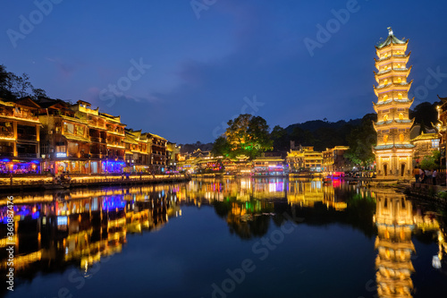 Chinese tourist attraction destination - Feng Huang Ancient Town (Phoenix Ancient Town) on Tuo Jiang River with Wanming Pagoda illuminated at night. Hunan Province, China photo