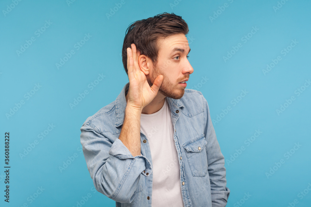 What? I can't hear! Portrait of man in worker denim shirt holding hand near ear and listening carefully, having hearing problems, deafness and misunderstanding in communication. studio shot isolated What? I can't hear! Portrait of man in worker denim shirt holding hand near ear and listening carefully, having hearing problems, deafness and misunderstanding in communication. studio shot isolated