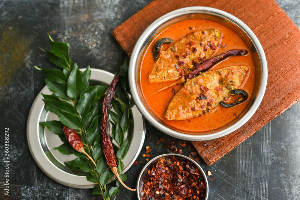 Top view of traditional Goan Pomfret or King fish curry Goa India on dark or black background. Hot and spicy homemade Kerala fish curry yellow curry made using coconut milk , gambooge, turmeric.  - obrazy, fototapety, plakaty 