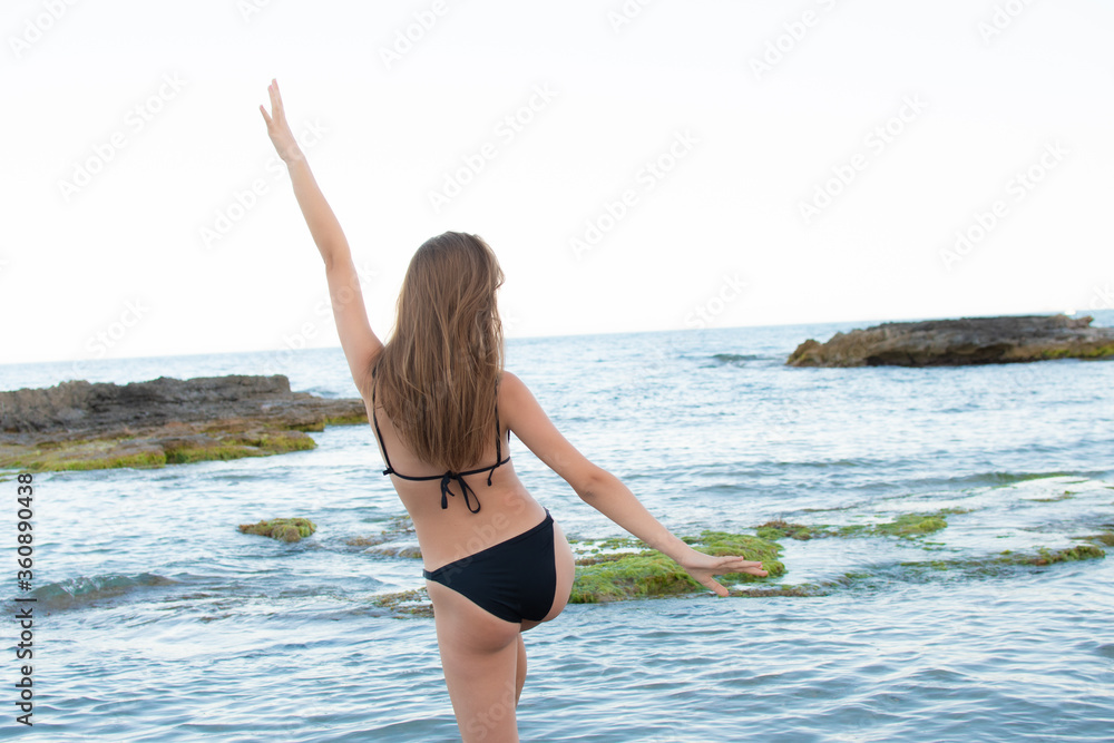 Naklejka premium Pretty woman in black bikini doing a funny gesture on the beach