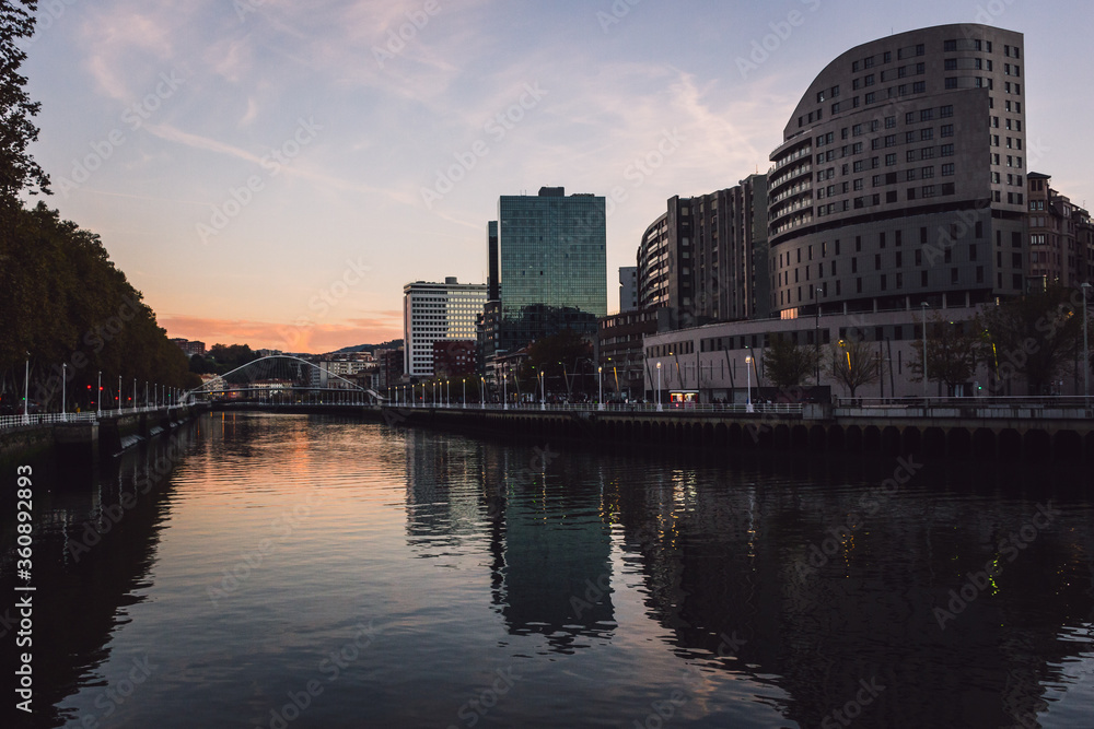 Modern city (Bilbao) with skyscrapers next to river at sunset Modern city (Bilbao) with skyscrapers next to river at sunset