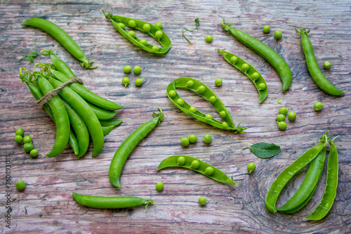 Fresh green peas - pods on a rustic wooden table. Summer harvest. 