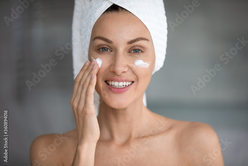 Portrait of young lady after shower use new revitalizing facial beauty product, millennial woman apply moisturizing cream or mask on face for healthy glowing skin, skincare, cosmetology concept