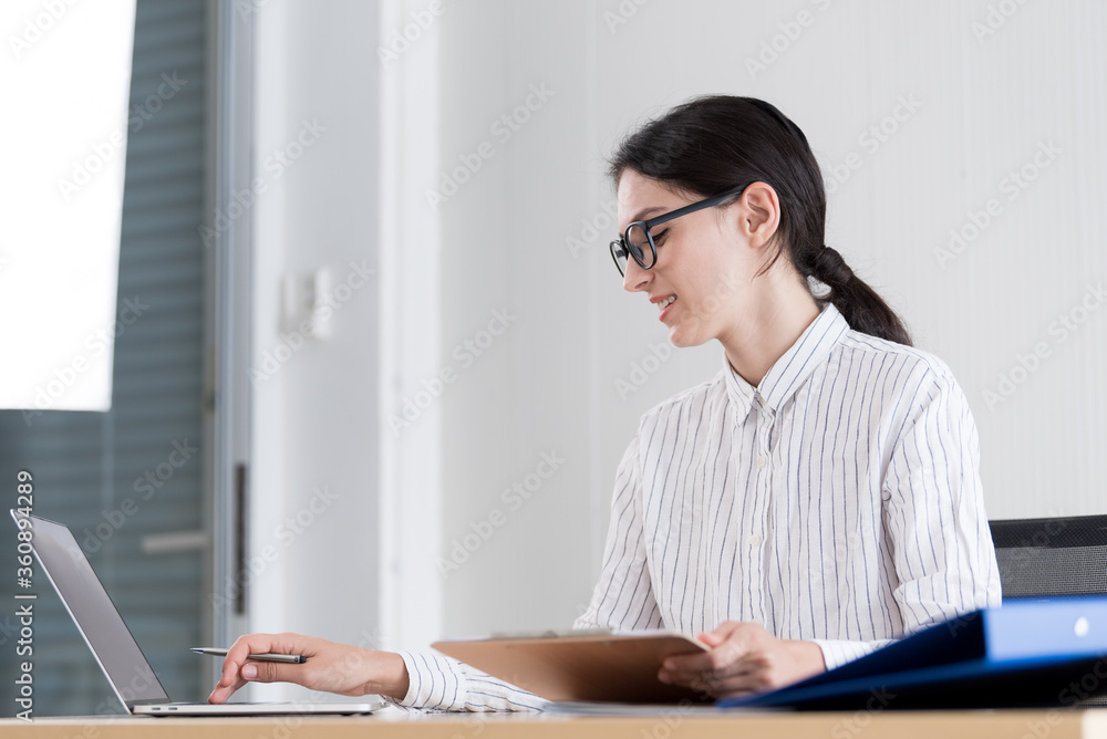 A businesswoman wearing glasses working with smiling and happiness at the office. A businesswoman wearing glasses working with smiling and happiness at the office.