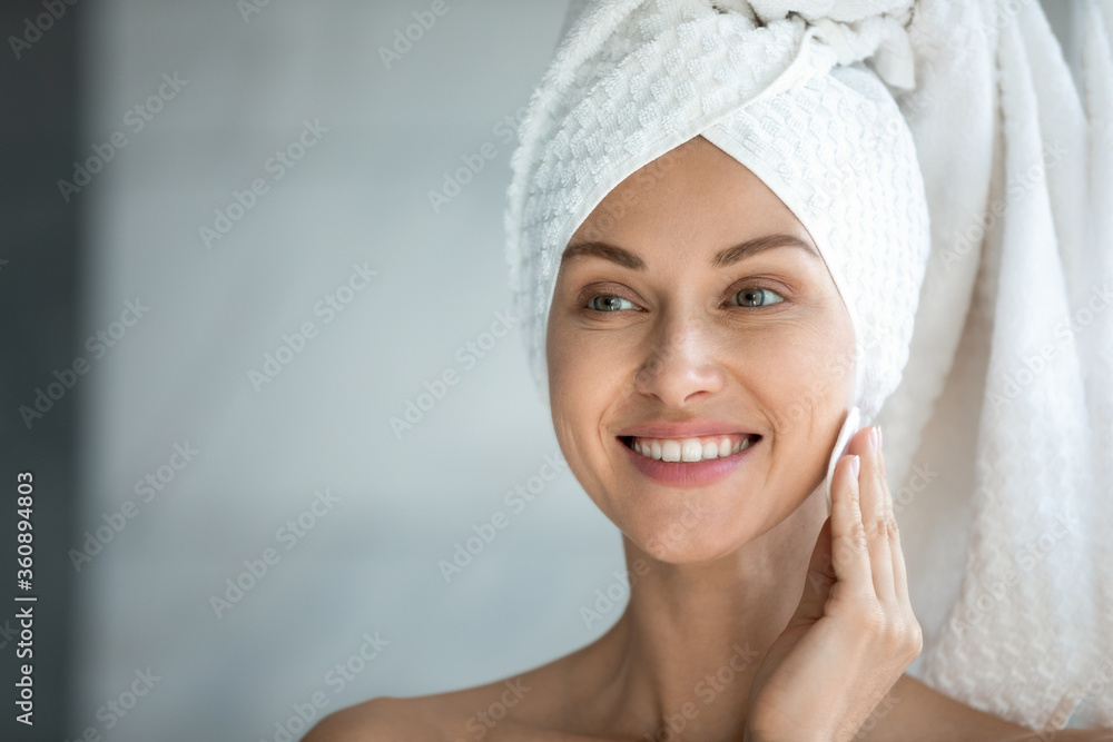 Smiling young woman after shower look in mirror make beauty facial procedures in bathroom, happy beautiful millennial female apply tonic or lotion on healthy skin, skincare, cosmetology concept Smiling young woman after shower look in mirror make beauty facial procedures in bathroom, happy beautiful millennial female apply tonic or lotion on healthy skin, skincare, cosmetology concept