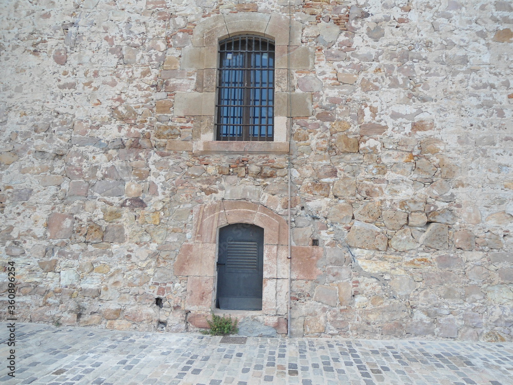 stone wall with wooden windows of the Montjuic Castle, Barcelona, Spain