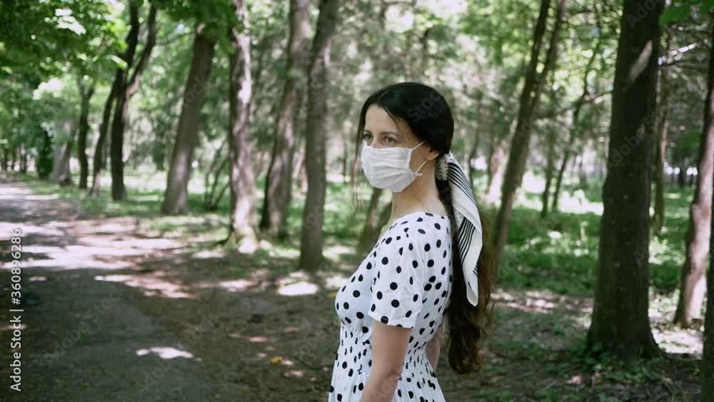 beautiful young woman walking in Park in summer in protective face mask beautiful young woman walking in Park in summer in protective face mask
