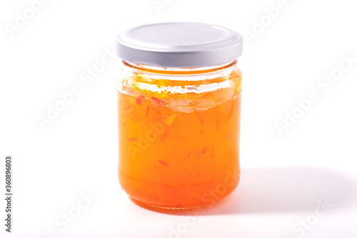 Orange jam in a glass bottle on a white background