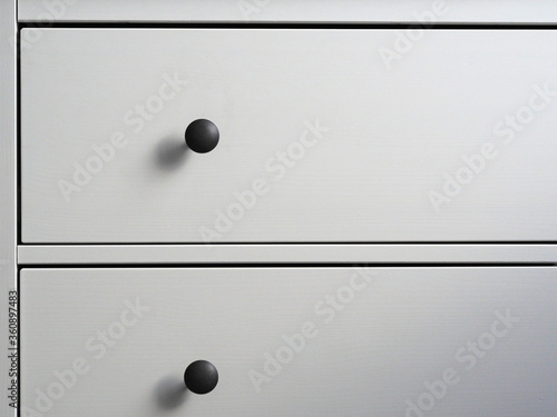 close-up of a modern white wooden chest of drawers with black handles. Minimalism, modern interior