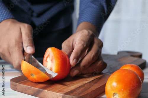 Hand Of Person Cutting Tomatoes On Chopping Board 