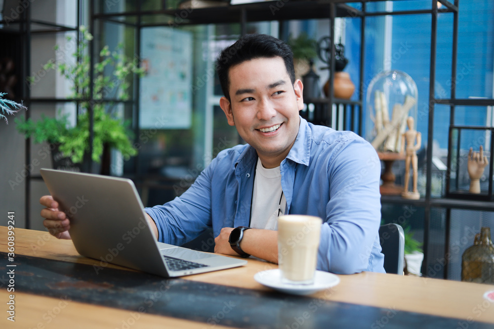 custom made wallpaper toronto digitalYoung Asian Man in blue shirt working with laptop in coffee shop cafe smile and happy face