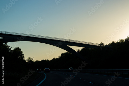 High arch bridge above dual carriageway road during sunset