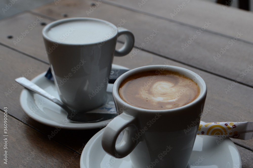 Obraz premium Cups of coffee with milk on a wooden table in a terrace of Gijon.