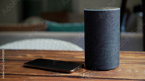 Dark grey Black Amazon Alexa Echo and smart phone on the wooden table in a living room,