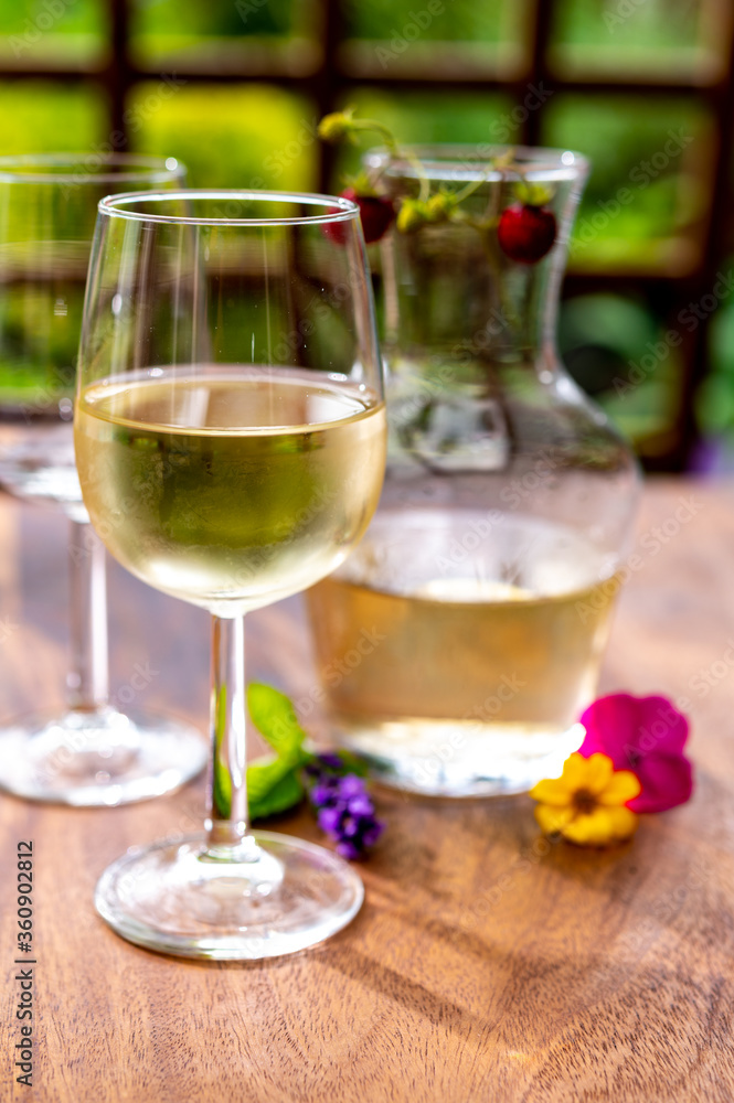 Summer tasting of cold white wine on sunny garden terrace with wooden pergola Summer tasting of cold white wine on sunny garden terrace with wooden pergola