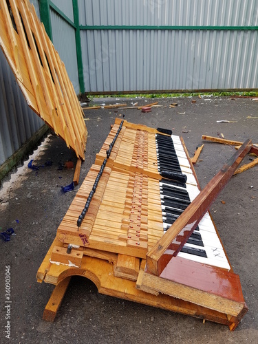 A broken musical instrument in a trash can. Piano in the trash. photo