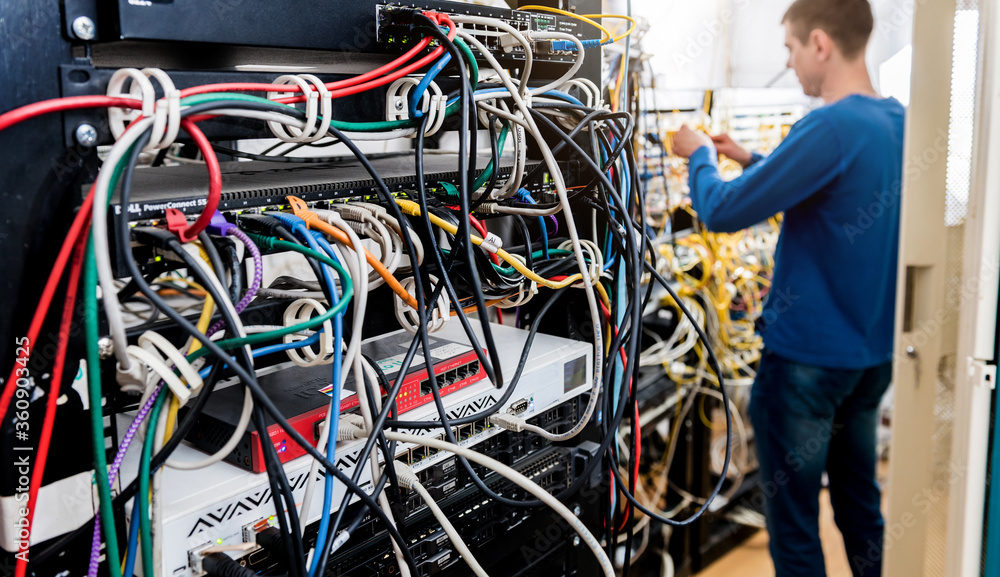 Network engineer working in server room. Connecting network cables to switches Network engineer working in server room. Connecting network cables to switches