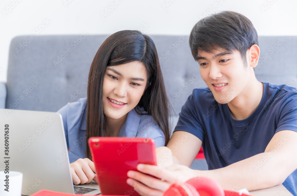 Young couple sitting and using technology communication by smartphone tablet and laptop computer in living room