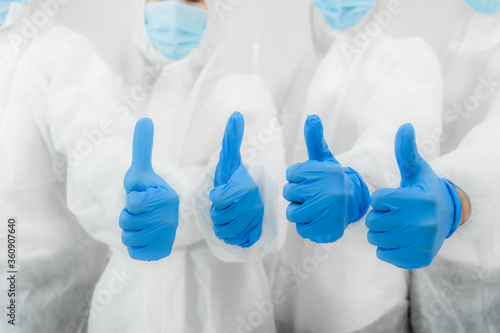Team of medical scientific researcher standing wear safety suit and personal protective equipment with thumbs up in lab.